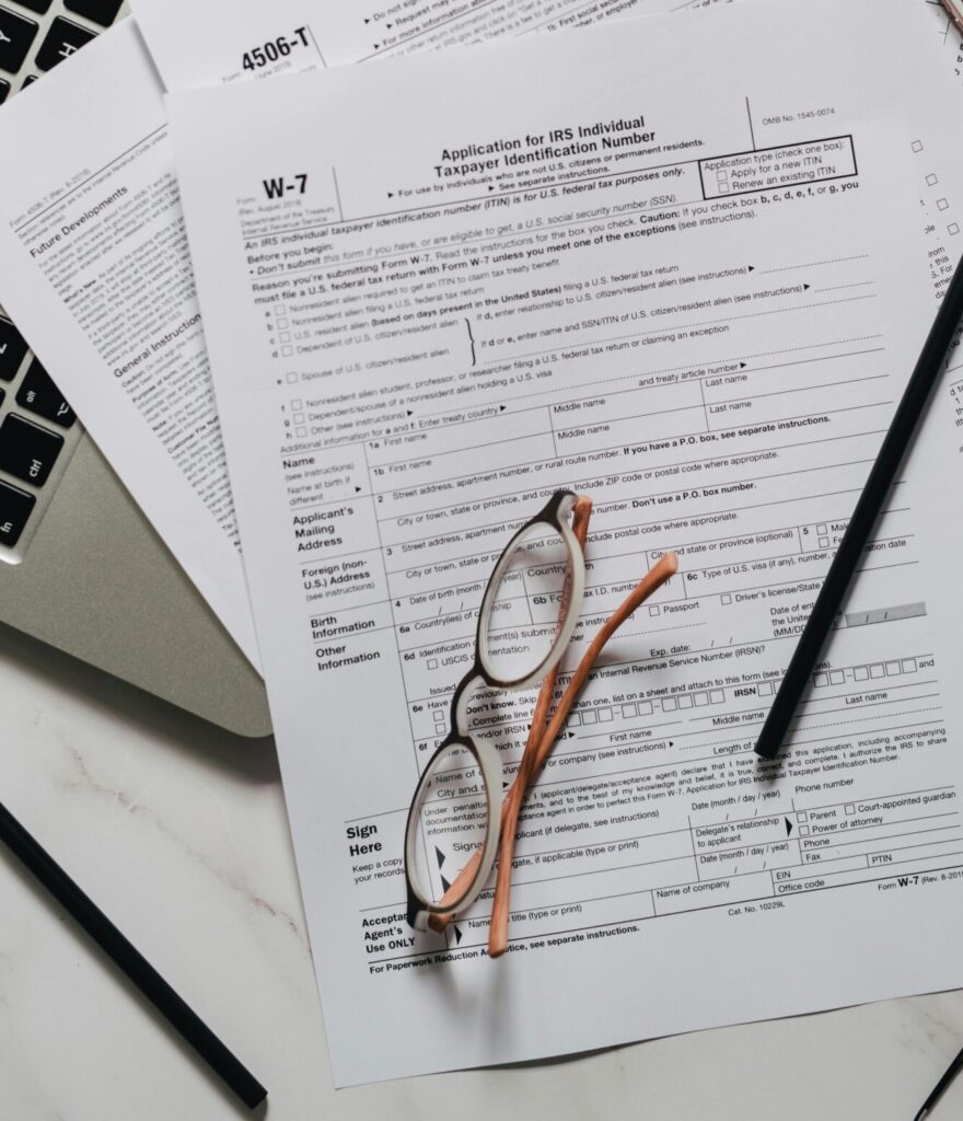 Arrangement of tax forms, calculator, and office supplies on a marble surface, top view.